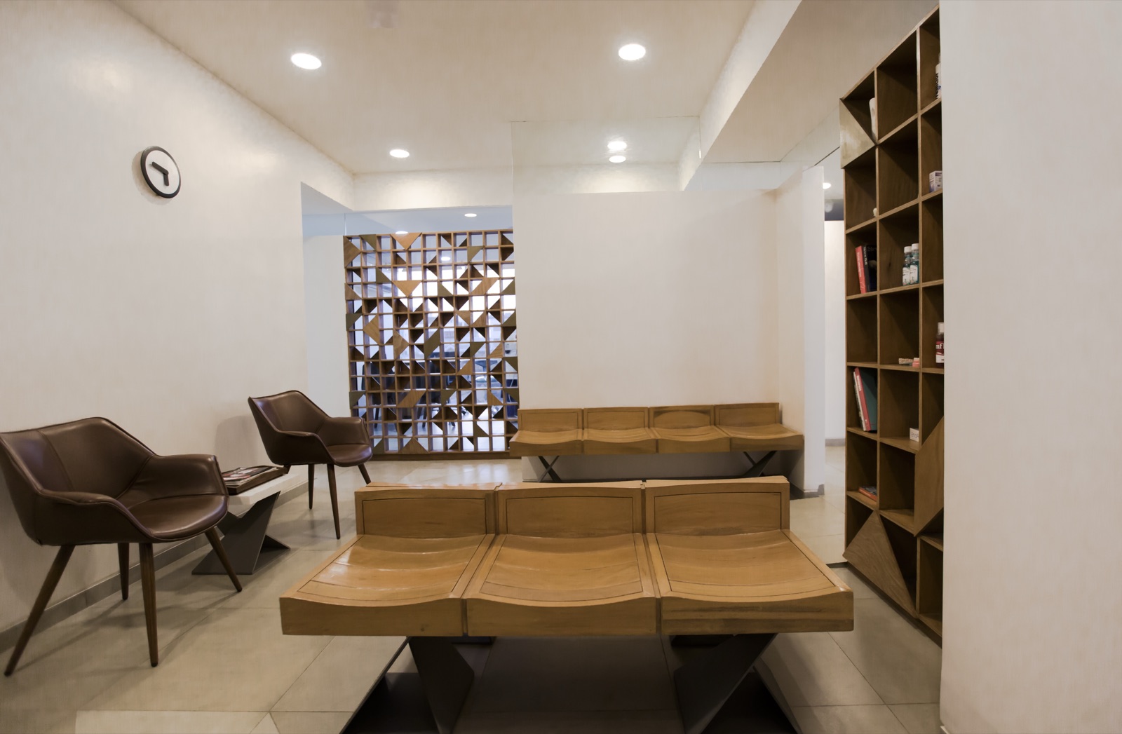 Lounge with sculptural solid-wood benches, a geometric timber screen and leather chairs by WOODWORKS Interior, Bengaluru