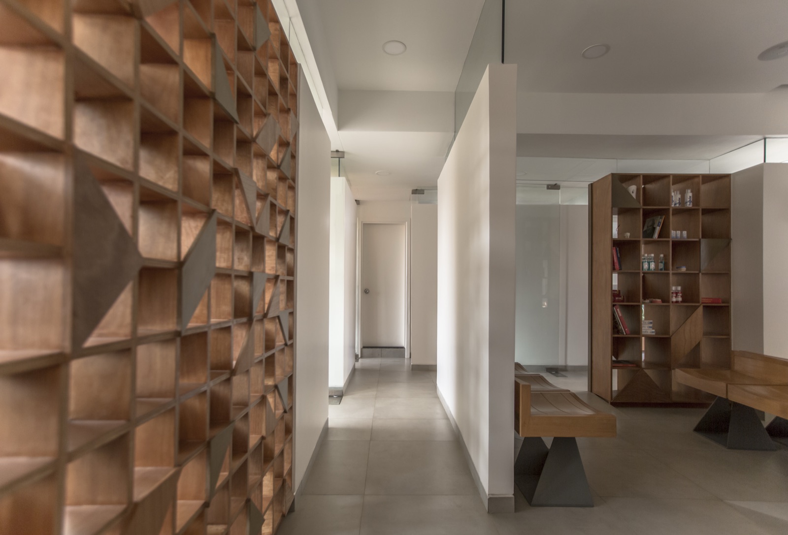 Wooden lattice partition wall with an integrated bench and open shelving by WOODWORKS Interior, Bengaluru
