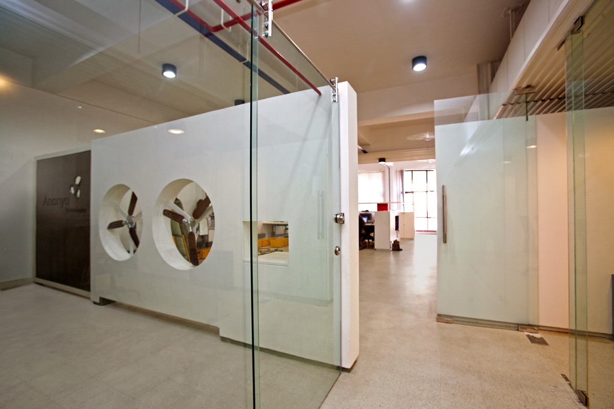 Sculptural white feature partition inset with wooden-propeller portholes in a bespoke workspace by WOODWORKS Interior, Bengaluru